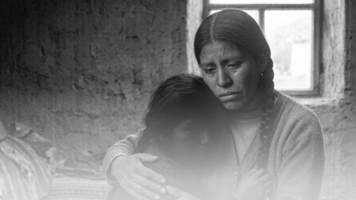 Madre abraza a su hija en una vivienda andina, fotografía en blanco y negro